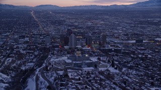 AX128_015E - 5.5K aerial stock footage fly over north side of the state capitol building to approach Downtown SLC with winter snow at sunset, Utah