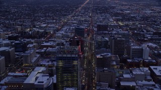 AX128_025E - 5.5K aerial stock footage of following Main Street over office buildings in Downtown Salt Lake City, Utah in winter at twilight