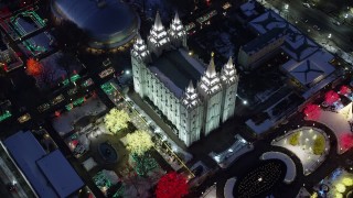 AX128_081 - 5.5K stock footage aerial video bird's eye orbit of Salt Lake Temple with colorfully lit trees with winter snow at night, Downtown SLC, Utah