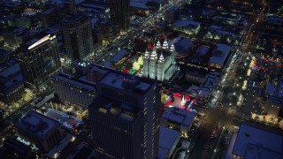 AX128_085 - 5.5K stock footage aerial video orbit Church Building by Salt Lake Temple lit for Christmas with winter snow at night, Downtown SLC, Utah