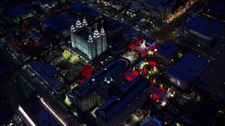 AX128_086E - 5.5K aerial stock footage orbit fountains and Christmas lights at Salt Lake Temple with winter snow at night, Downtown Salt Lake City, Utah