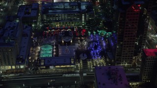 AX128_094 - 5.5K stock footage aerial video orbit ice skating rink and Christmas tree at Gallivan Center in winter at night, Downtown SLC, Utah