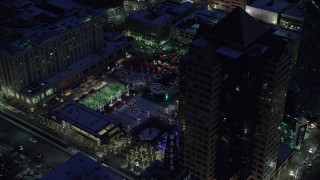 AX128_095 - 5.5K stock footage aerial video orbit office buildings and Gallivan Center, lit for Christmas in winter at night. Downtown SLC, Utah