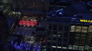 AX128_096 - 5.5K stock footage aerial video orbit office building and reveal Gallivan Center lights and ice rink at night, Downtown Salt Lake City, Utah