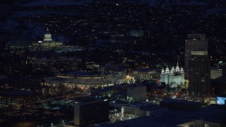 AX128_104 - 5.5K stock footage aerial video orbit capitol building, conference center, zoom in on Salt Lake Temple in winter, night, Downtown SLC, Utah