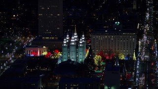 AX128_104E - 5.5K aerial stock footage orbit capitol building, conference center, zoom in on Salt Lake Temple in winter, night, Downtown SLC, Utah