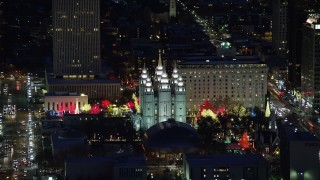 AX128_106 - 5.5K stock footage aerial video orbit Salt Lake Temple with bright Christmas lights at night in winter, Downtown Salt Lake City, Utah