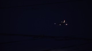 AX128_115 - 5.5K stock footage aerial video track jet descending toward the SLC Airport runway for landing at night in winter, Utah