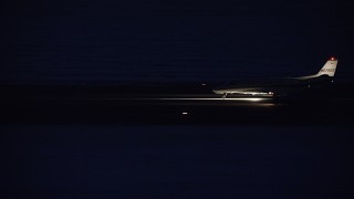 AX128_118 - 5.5K stock footage aerial video track private jet on airport runway at night in winter, Salt Lake City International Airport, Utah
