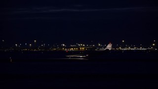 AX128_118E - 5.5K aerial stock footage track private jet on airport runway at night in winter, Salt Lake City International Airport, Utah