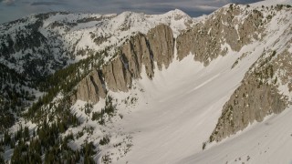 AX129_125E - 5.5K aerial stock footage of passing white slopes of Lone Peak in the snowy Wasatch Range, Utah