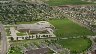 AX130_026E - 5.5K aerial stock footage of orbiting West Hills Middle School and grass fields, West Jordan, Utah