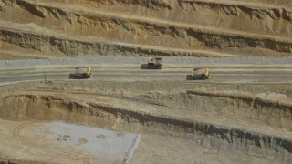 AX130_054 - 5.5K aerial stock footage of flying by gravel haulers in Kennecott Copper Mine, aka Bingham Canyon Mine, Utah