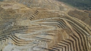 AX130_055E - 5.5K aerial stock footage of flying away from gravel haulers, Bingham Canyon Mine, Utah