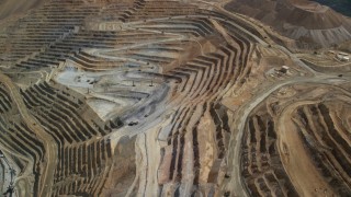 AX130_056 - 5.5K aerial stock footage of reverse view of gravel haulers, Bingham Canyon Mine, Utah