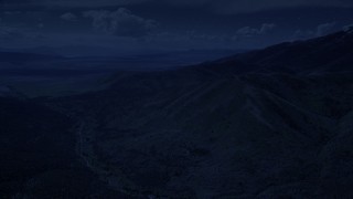 AX130_064_DFN - Aerial stock footage of 4K day for night color corrected aerial footage of approaching rugged mountain ridges, Oquirrh Mountains, Utah