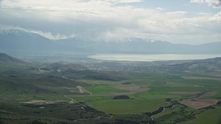 AX130_068E - 5.5K aerial stock footage of flying by green farmland, Utah Lake, Utah