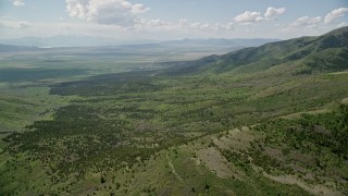 AX130_070E - 5.5K aerial stock footage of flying over green hills, Oquirrh Mountains, Utah