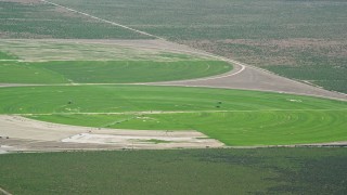 AX130_078 - 5.5K aerial stock footage of flying by circular crop fields, tractors, Cedar Fort, Utah