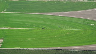 AX130_079 - 5.5K aerial stock footage of passing by circular crop fields, tractors, Cedar Fort, Utah