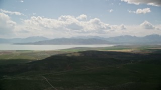 AX130_080E - 5.5K aerial stock footage of flying by farmland, distant mountain range and Utah Lake, Utah