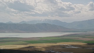 AX130_082E - 5.5K aerial stock footage of flying by circular crop fields, distant snow-capped peak and Utah Lake, Utah