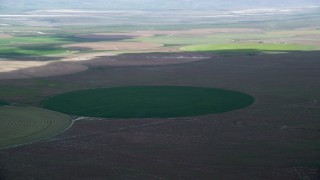AX130_084 - 5.5K aerial stock footage of flying by green circular crop field, Elberta, Utah