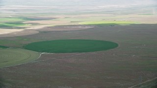 AX130_084E - 5.5K aerial stock footage of flying by green circular crop field, Elberta, Utah