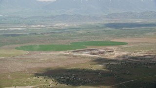AX130_087E - 5.5K aerial stock footage of passing by two green circular crop fields, Elberta, Utah