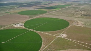 AX130_093E - 5.5K aerial stock footage of approaching circular crop fields and tilt to one of them, Elberta, Utah