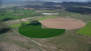 AX130_099 - 5.5K aerial stock footage of approaching Pac-man shaped circular crop field, Elberta, Utah