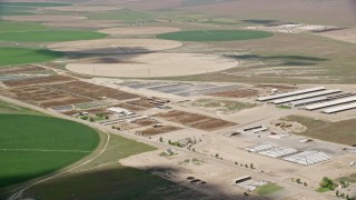 AX130_101E - 5.5K aerial stock footage of flying by circular crop fields, greenhouses, ponds, Elberta, Utah