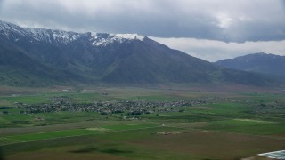 AX130_107 - 5.5K aerial stock footage of flying by small town at the base of Wasatch Range, Mona, Utah