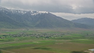 AX130_107E - 5.5K aerial stock footage of flying by small town near the Wasatch Range, Mona, Utah