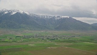 AX130_109E - 5.5K aerial stock footage of a view of a small rural town by base of Wasatch Range, Mona, Utah