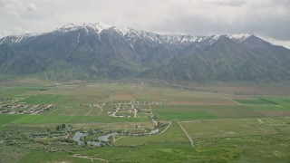 AX130_113E - 5.5K aerial stock footage of flying by Burraston Ponds, small rural town, Wasatch Range, Mona, Utah