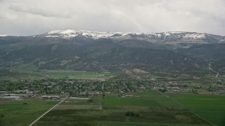 AX130_138E - 5.5K aerial stock footage of passing small rural town, Wasatch Range in the background, Ephraim, Utah