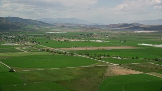 AX130_143E - 5.5K aerial stock footage of approaching farmland, distant mountain ranges, Manti, Utah