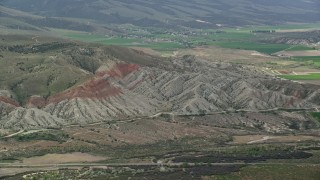 AX130_158E - 5.5K aerial stock footage of flying by rugged hills, farmland in background, Sterling, Utah