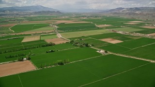 AX130_164E - 5.5K aerial stock footage fly over farmland, roads separating fields, Aurora, Utah