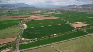 AX130_165 - 5.5K aerial stock footage fly over farmland, roads separating fields, Aurora, Utah