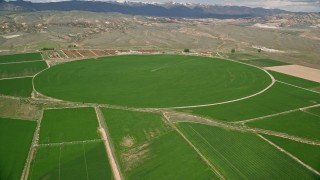 AX130_168 - 5.5K aerial stock footage of flying by green circular crop field, farmland, Aurora, Utah