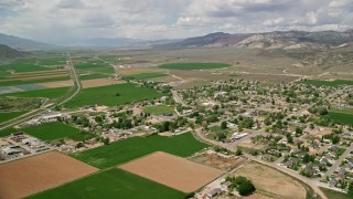 AX130_169E - 5.5K aerial stock footage of flying by small rural town, surrounded by farmland, Aurora, Utah