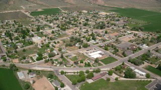 AX130_171 - 5.5K aerial stock footage of passing a small rural town, bordered by farmland, Aurora, Utah