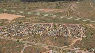 AX130_182 - 5.5K aerial stock footage of flying by cars in auto junkyard, surrounded by dry fields, Sigurd, Utah