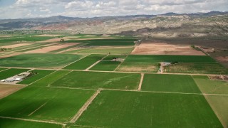 AX130_190 - 5.5K aerial stock footage of passing by farmland, brown hills, Richfield, Utah
