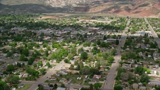 AX130_194E - 5.5K aerial stock footage of passing by shops, small town neighborhoods, Richfield, Utah