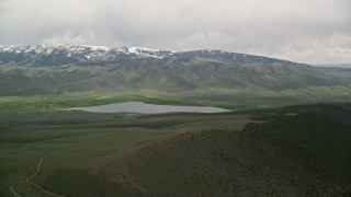 AX130_209E - 5.5K aerial stock footage of Koosharem Reservoir, snowy mountains, Fishlake National Forest, Utah