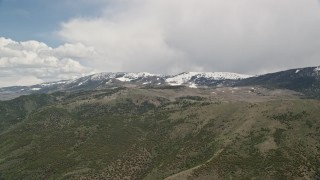 AX130_216E - 5.5K aerial stock footage of passing by snow-capped and tree-covered green mountains, Fishlake National Forest, Utah