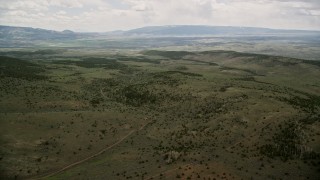 AX130_226E - 5.5K aerial stock footage of a wide view of green hills, trees, approaching country road, Fishlake National Forest, Utah
